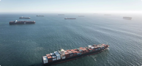 Вид с воздуха на скопление контейнеровозов в море в ясный день, один из кораблей несет логотип APL