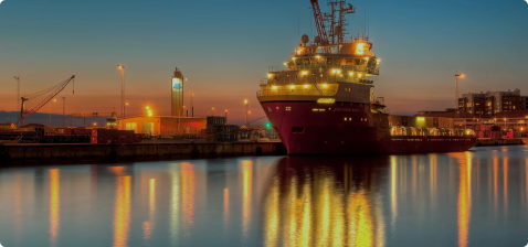 Порт с несколькими судами обеспечения, включая 'TOISA ELAN', на фоне золотого заката и портового крана на переднем плане, отражение в воде, драматическое освещение