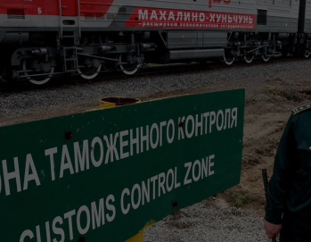 Зеленый знак таможенного контроля с надписью на русском и английском языке, установленный на железнодорожной платформе рядом с грузовым вагоном