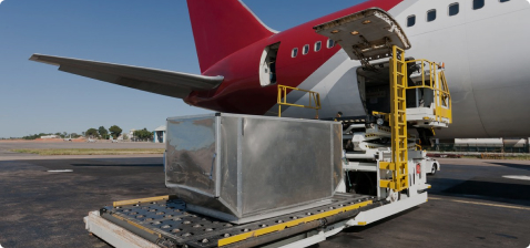 Вид на подъемник для загрузки самолетов, соединенный с красным самолетом; на заднем плане видна взлетно-посадочная полоса