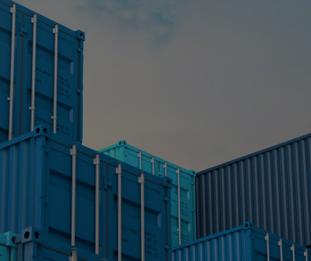 Сложенные друг на друга синие морские контейнеры на фоне голубого неба с легкими облаками, вид снизу вверх